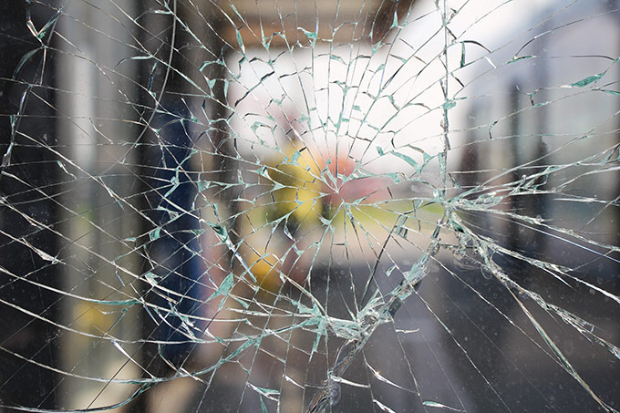 Photo of a shattered window, securely protected by the window tint covering it.